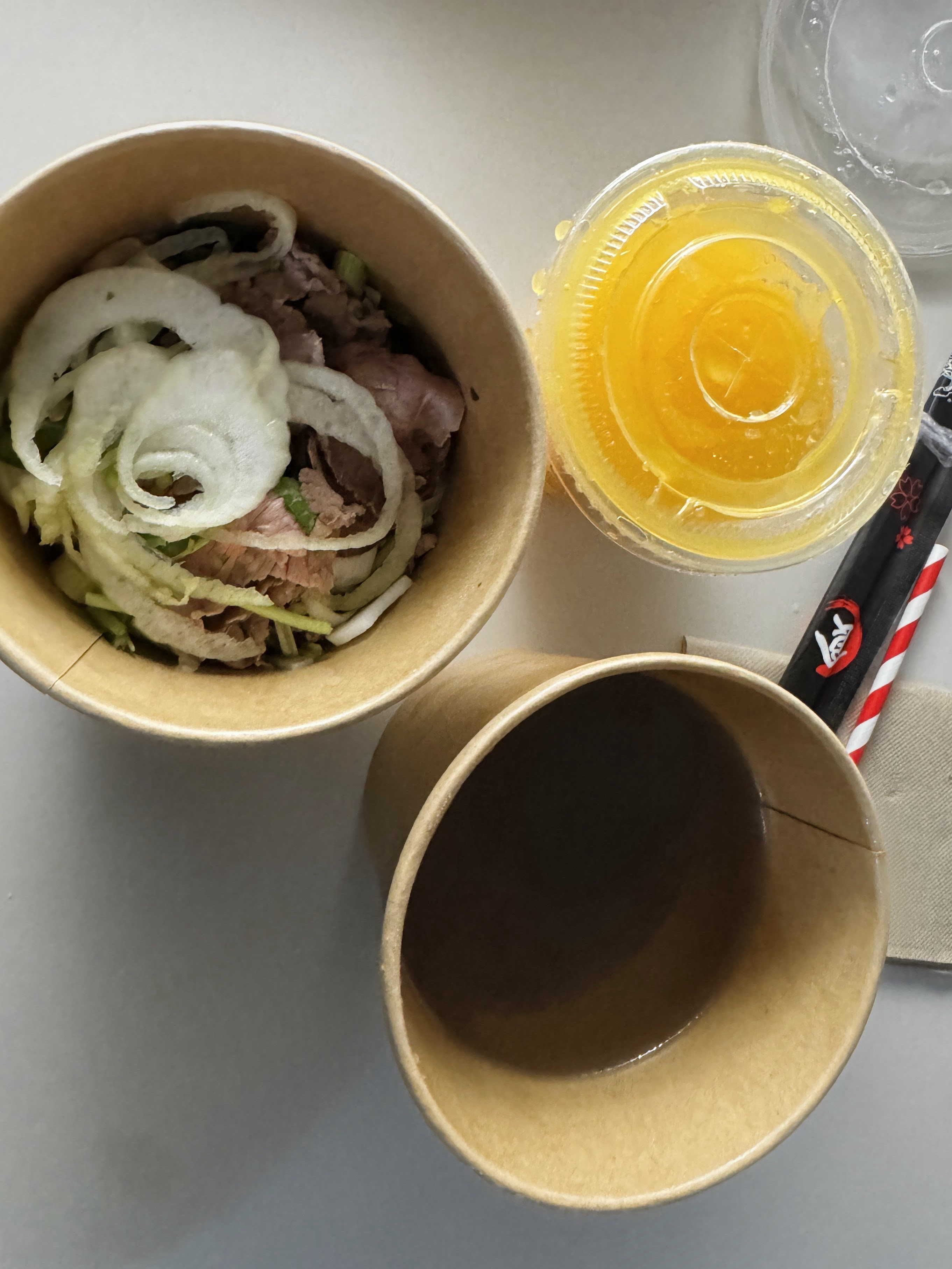 Overhead Korean beef rice bowl with orange juice, takeout lunch in Madrid.
