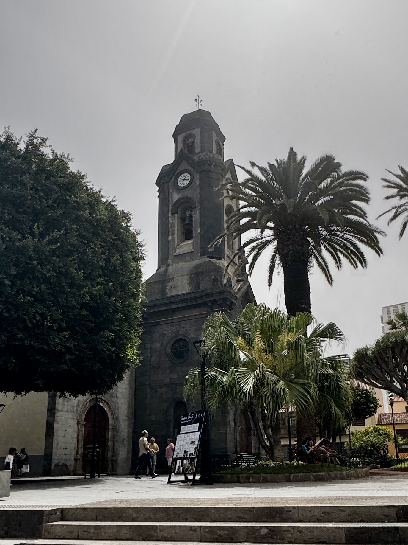 Street view in Tenerife with white buildings and palm trees under bright skies.