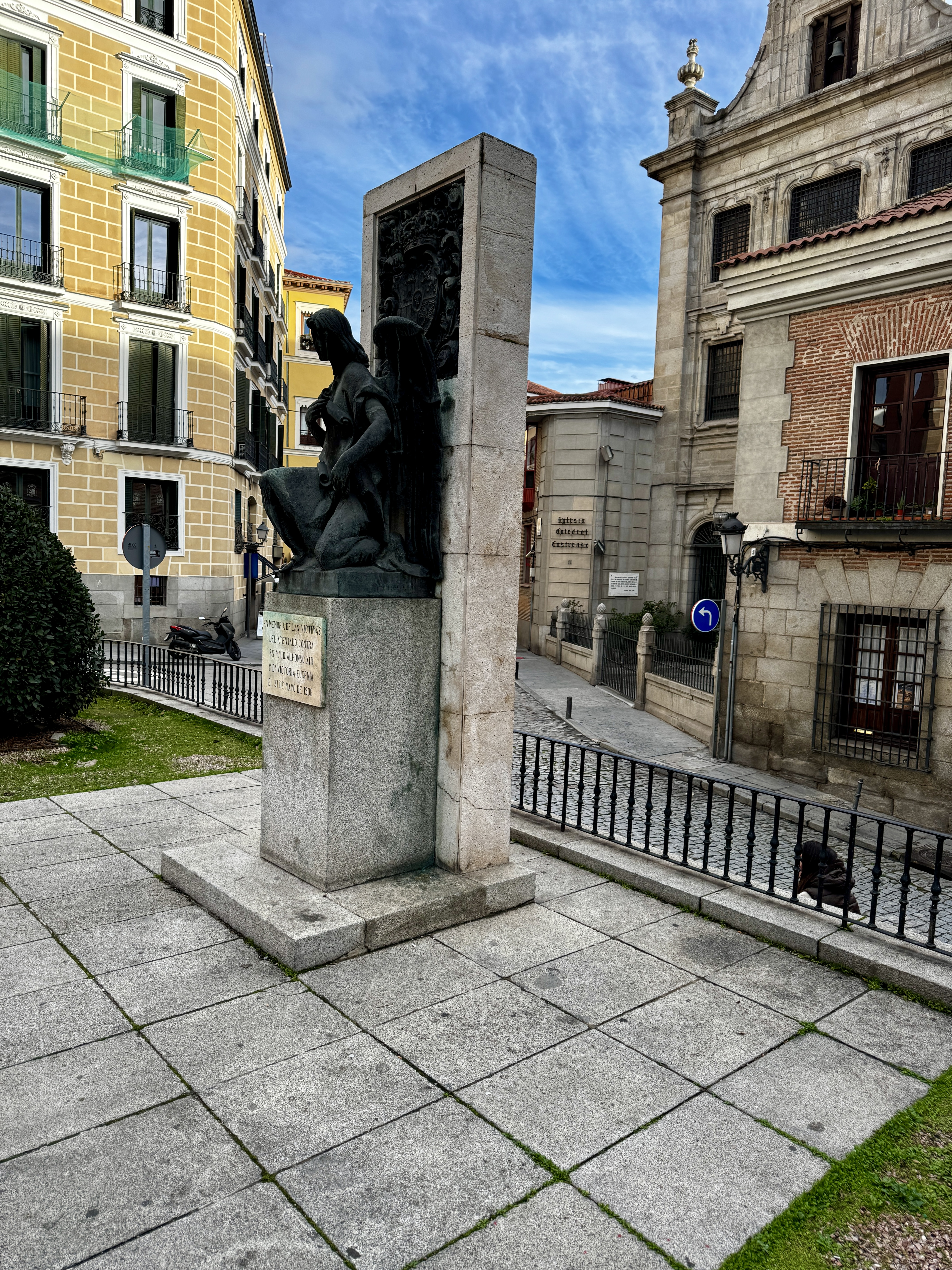 The facade of the Royal Palace of Madrid with ornate stone carvings and a large clock tower against a clear blue sky.